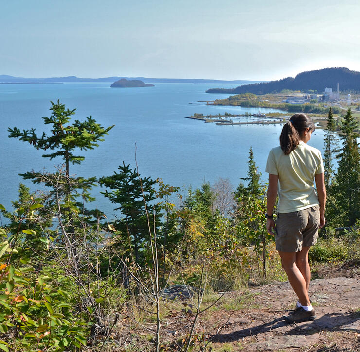 Woman standing on cliff top looking at view of Lake Superior.