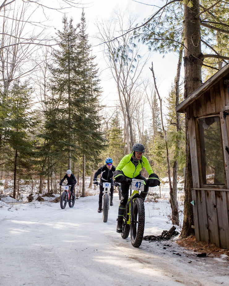 people ride fat bikes past a rustic forest structure at Mansfield Outdoor Centre