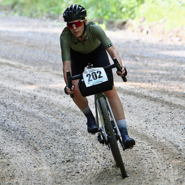 Woman pedalling bike on gravel road.