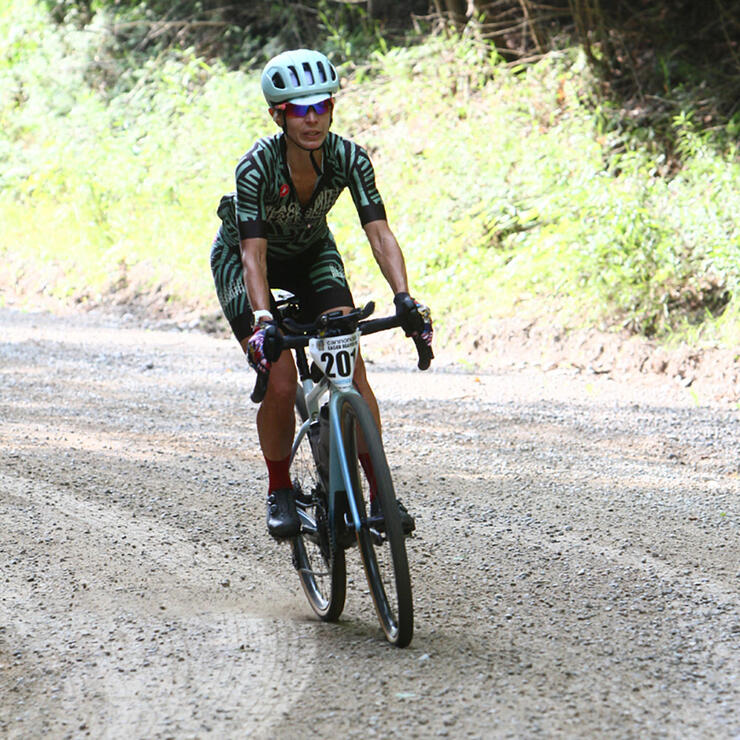 Woman riding bike on dirt road.