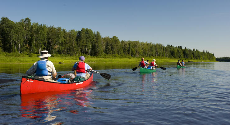 Group of canoe paddling on a wide northern river 