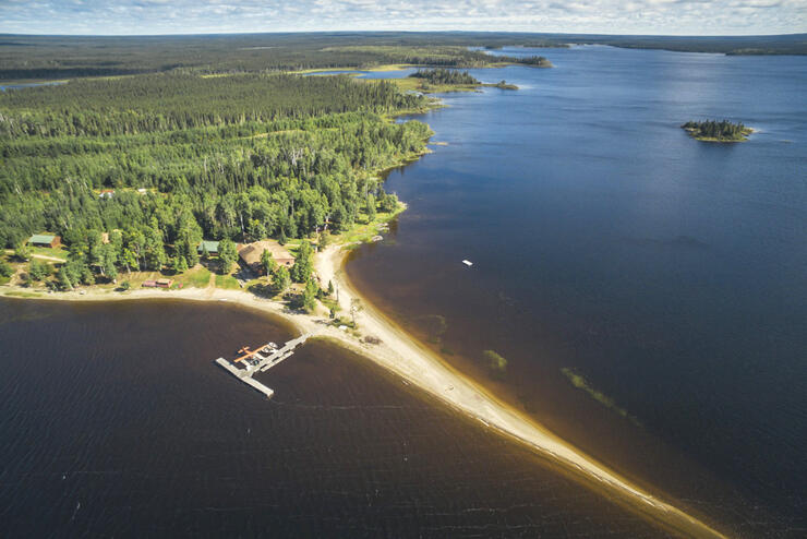 Aerial image of long sandy spit of land with large dock on beautiful lake