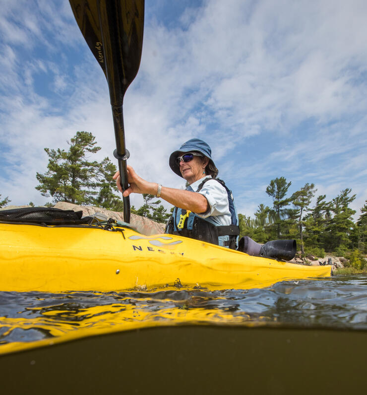 Looking up from the water at a woman in a kayak with a paddle