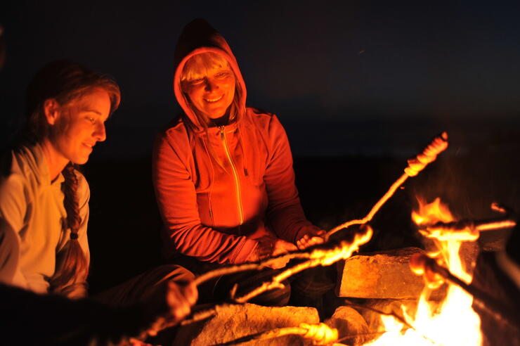 two people cooking bannock over a campfire