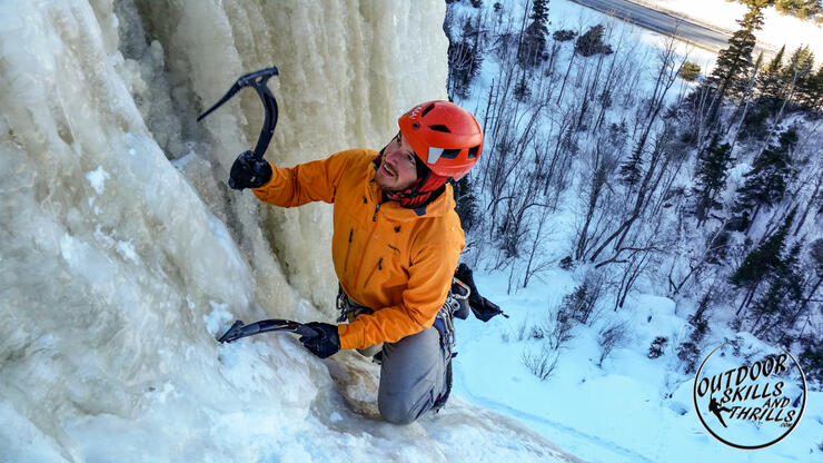 Man with ice picks climbing a frozen waterfall. 