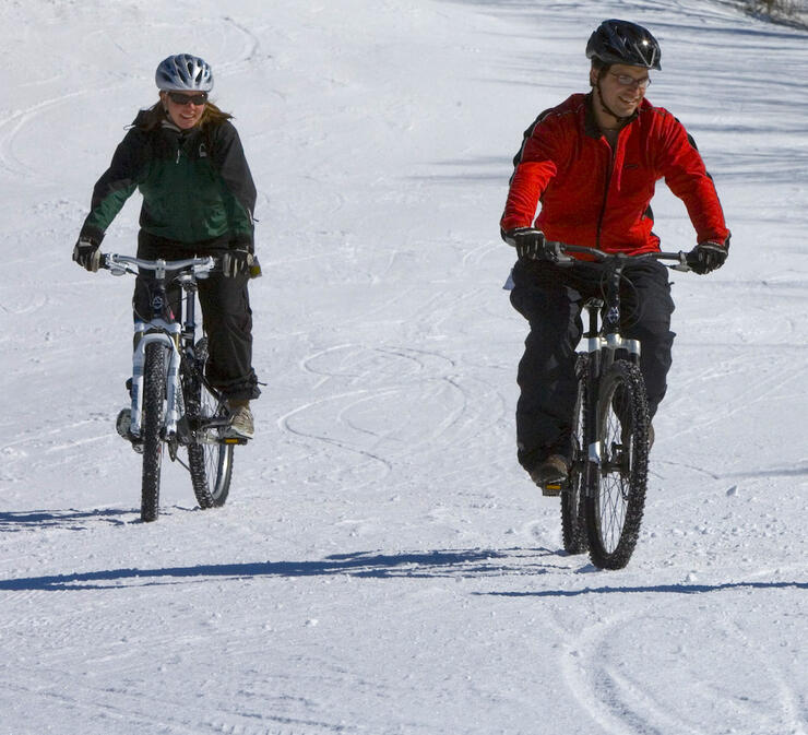Two people riding fat bikes on snow.