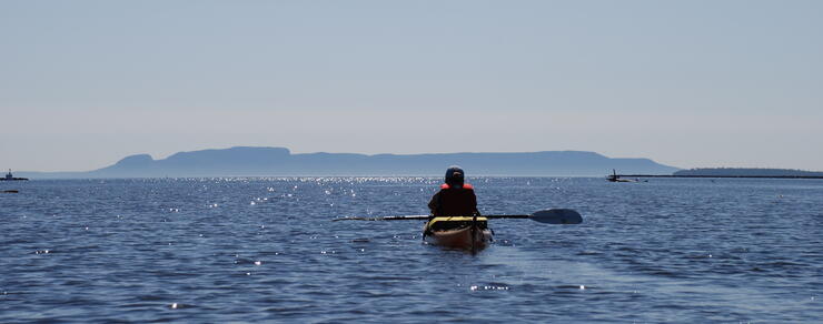 Kayaker paddling in front of Sleeping Giant