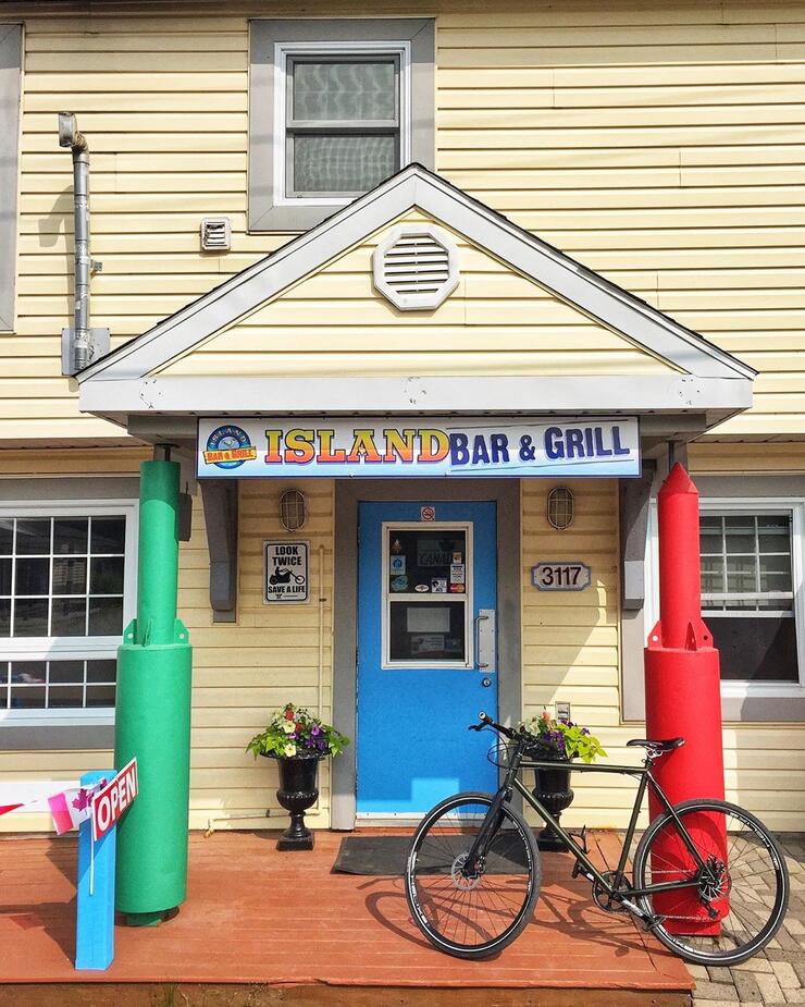 Front entrance of Island Bar and Grill with a bicycle leaning against a post. 