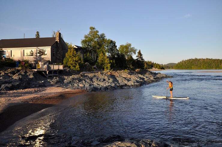 Woman paddling a SUP board in front of Rock Island Lodge. 