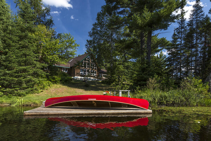 Canoe resting on a dock in front of a lodge. 