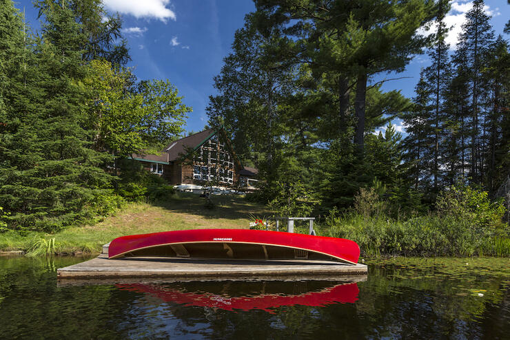 Canoe resting on a dock in front of a lodge.