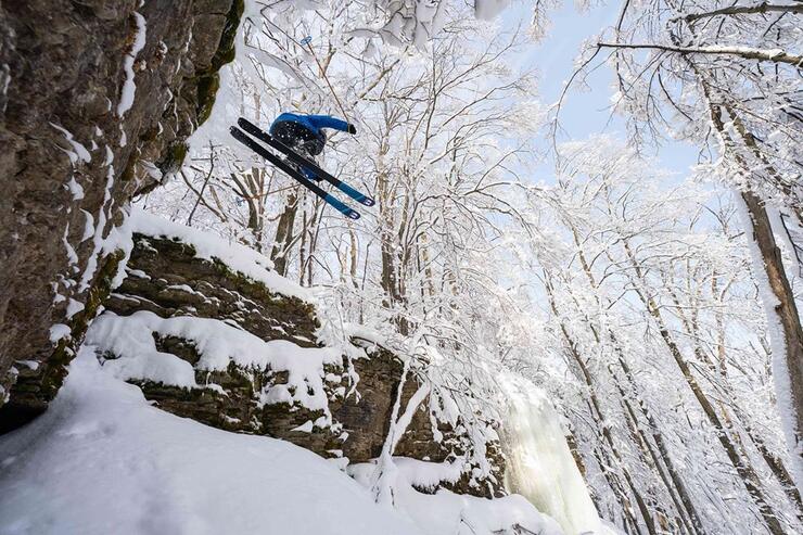 Man jumping with skiis off a rock cliff in winter. 