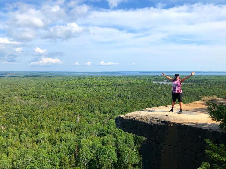 Woman standing on a rock outcrop with view of forest. 