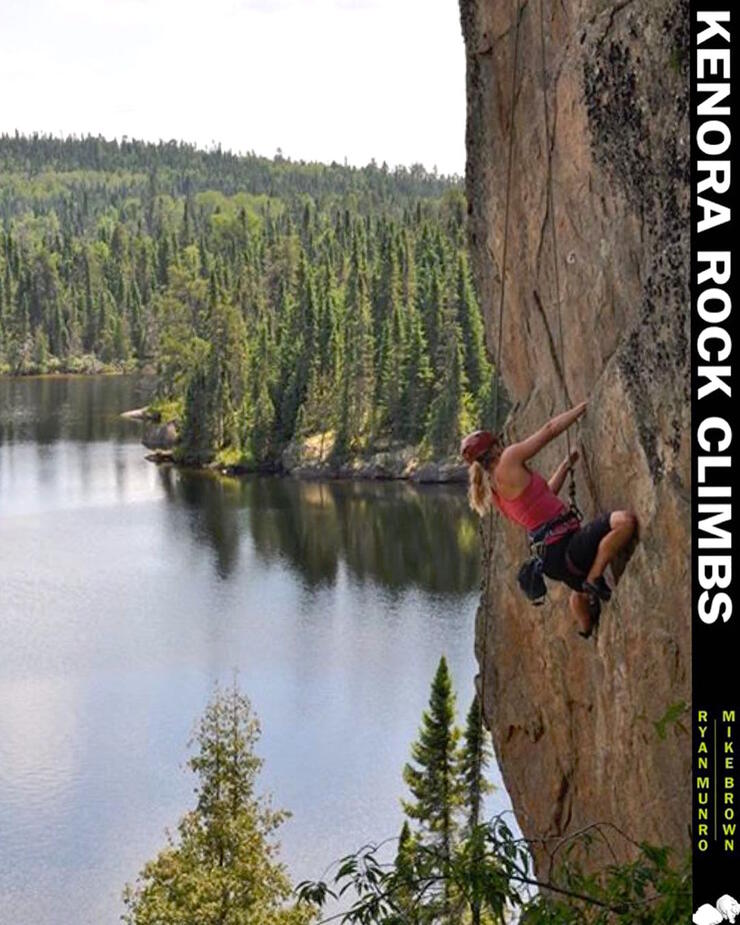 Woman climbing a vertical rock face with lake in background. 