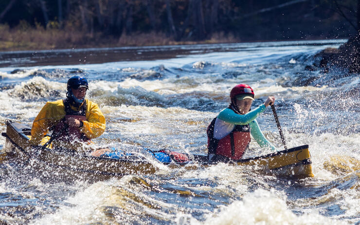 Father and Daughter paddling yellow canoe in big rapids 