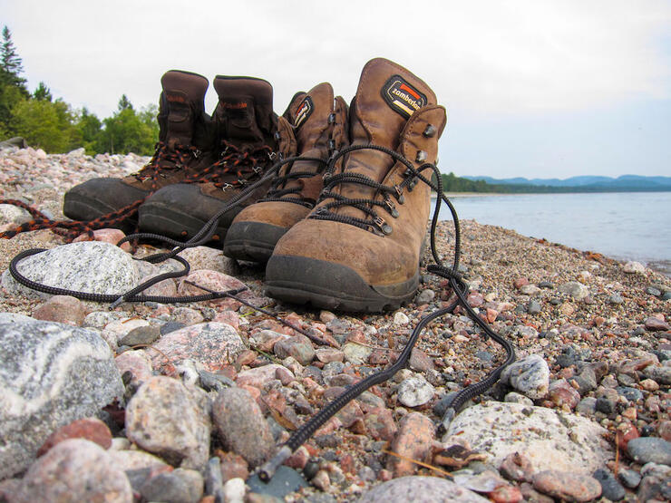 Two pairs of leather hiking boots on rocky beach
