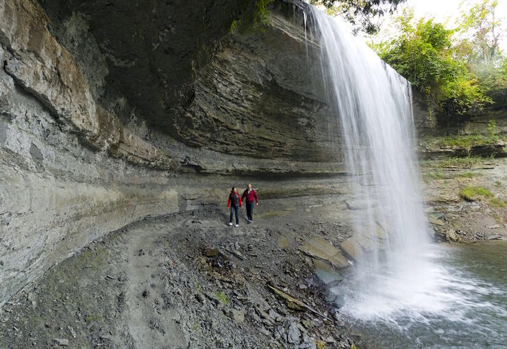 Couple walking on gravel path under waterfalls.