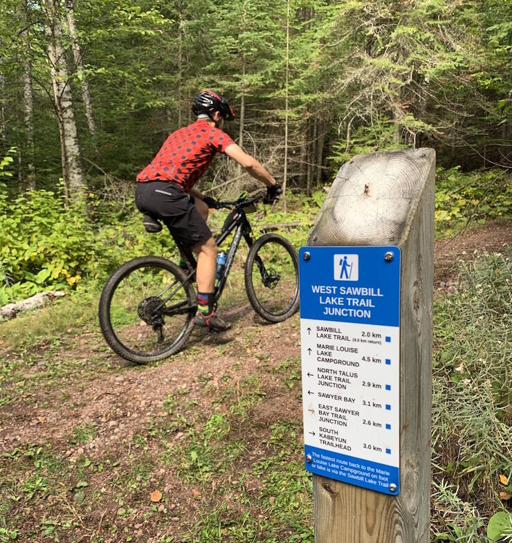 Man on bike riding past trail sign 