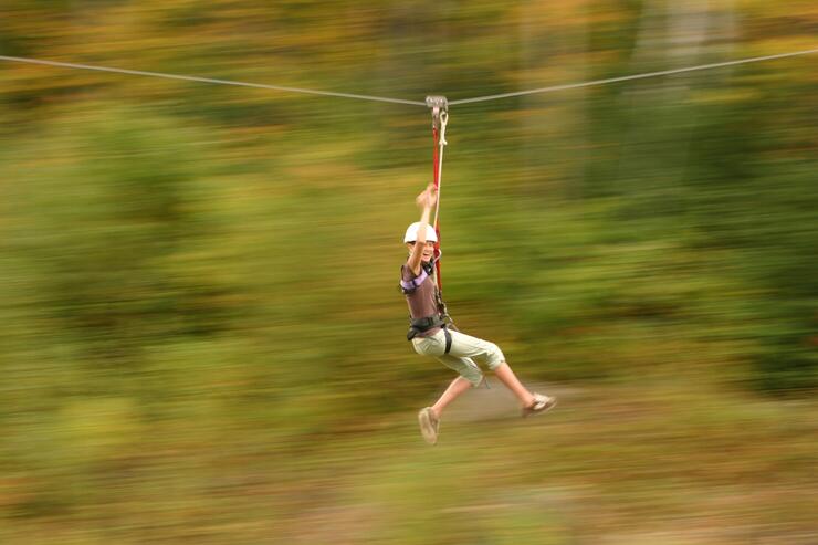 Young woman zipping on a cable. 