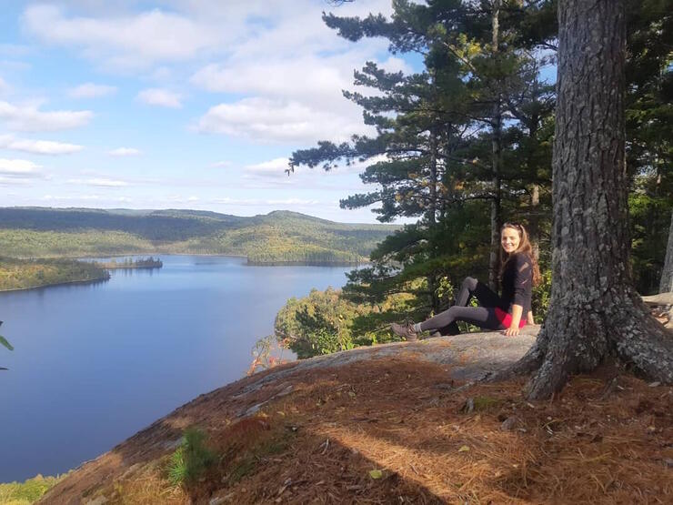 Woman sitting on a rock overlooking a lake. 