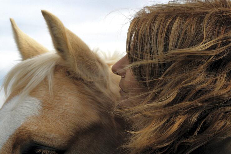 Close up a a woman hugging a horse