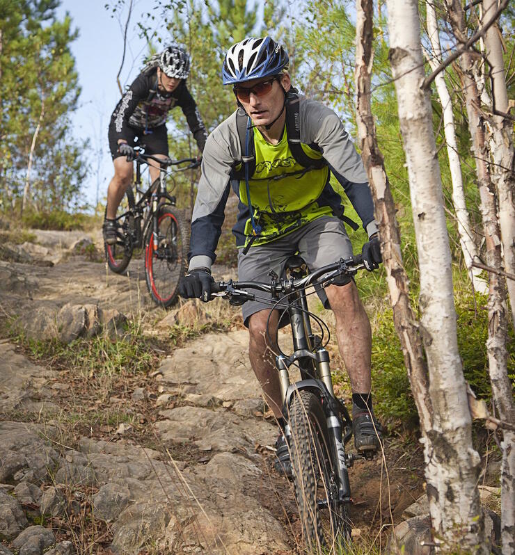 Mountain bikers riding on rough rocky trail. 