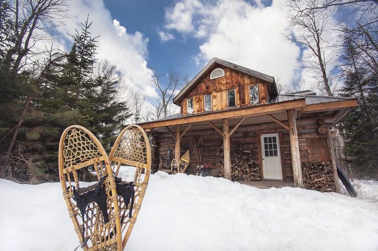 Log cabin lodge in snowy winter with a pair of snowshoes in front. 