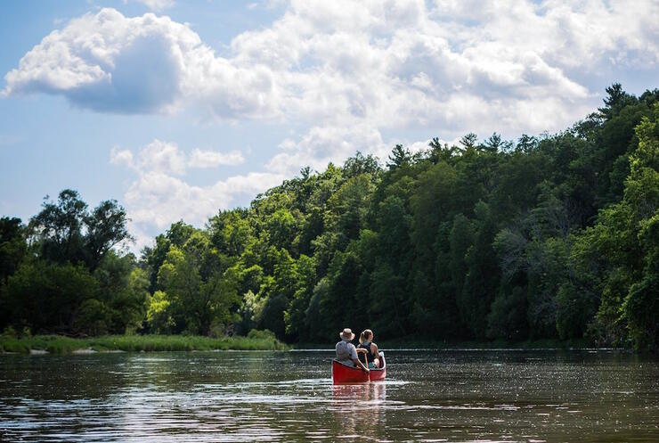 two people in a red canoe on a peaceful river 