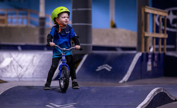 A young boy on a bike on a indoor pump track