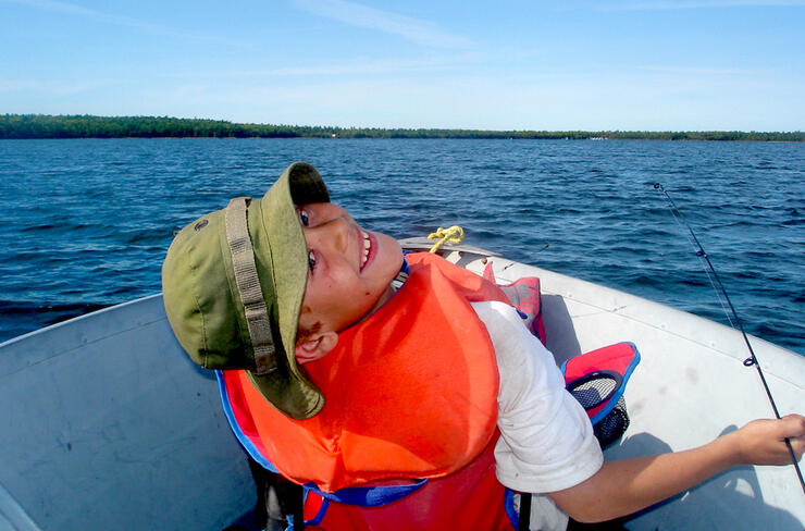 Young boy in lifejacket in fishing boat on a lake
