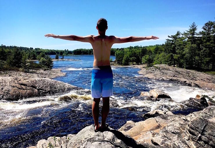 Young man standing with his arms outstretched, overlooking the Moon River. 