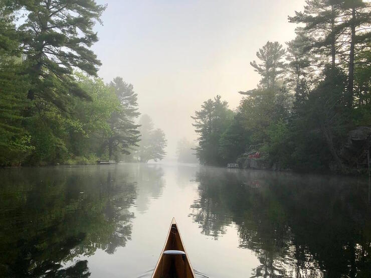 Bow of canoe travelling on a misty river. 