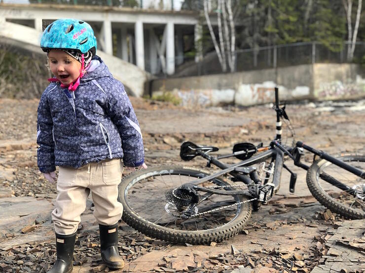 Young girl with bicycle helmet looking at rocks 