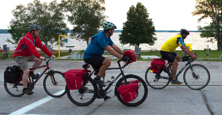 Three cyclists riding bikes with cycling packs. 