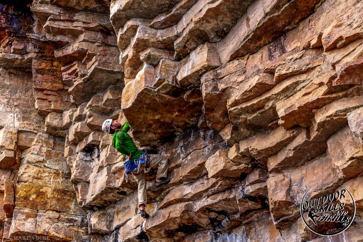 Man climbing a rugged vertical rock face.