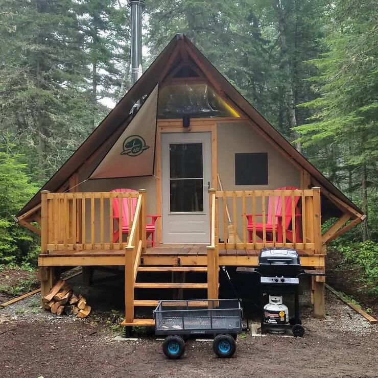 Wooden A-frame cabin with front deck.