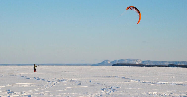 Person snowkiting on a frozen lake. 