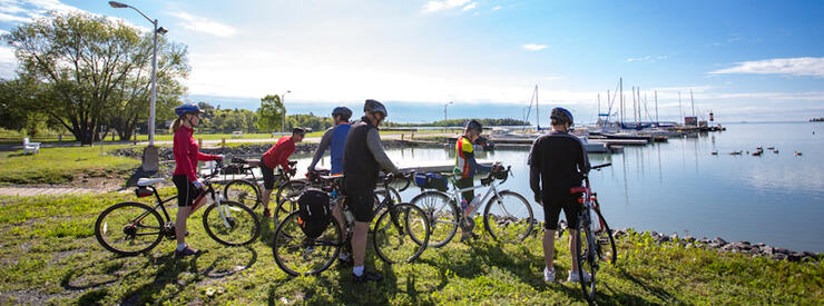 Group of cyclists standing with bikes looking a beautiful harbour with sail boats