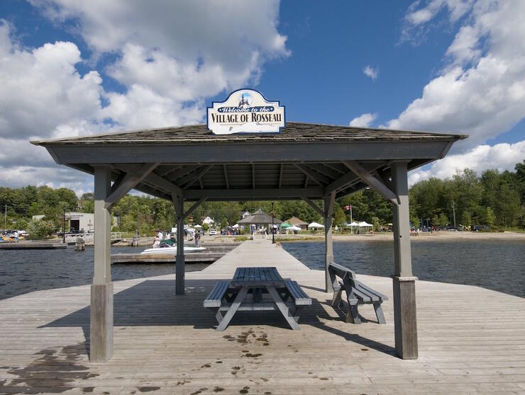 Looking at a pavillion, with Village of Rosseau sign,at the end of a dock