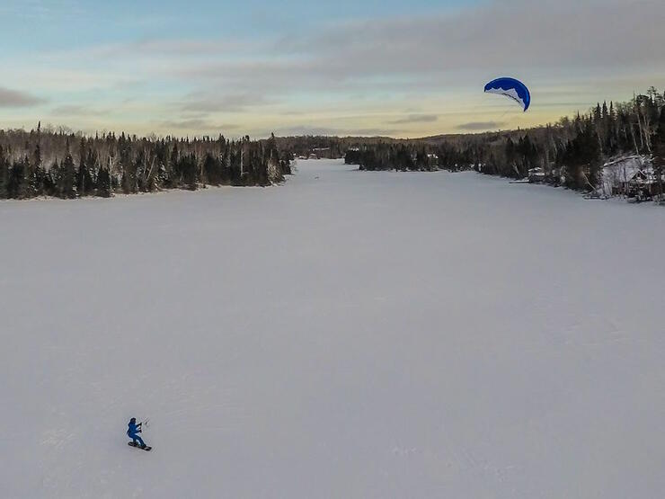 Aeral shot of person on snowboard - snowkiting on small lake