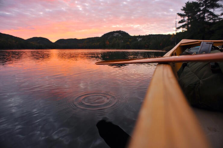 Side of canoe and paddle - beautiful sunset on lake. 