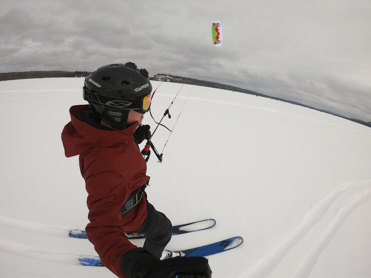 Close up of person in winter gear snowkiting. 