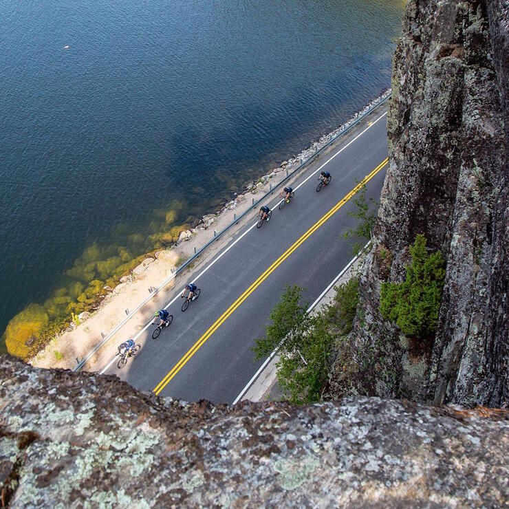 View from top of cliff looking down on cyclists on a road. 