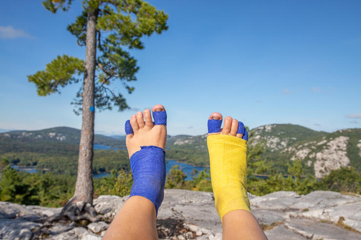 Looking at 2 feet covered in blue and yellow bandages.