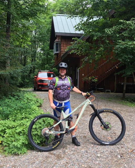 Man stands with mountain bike outside a cabin
