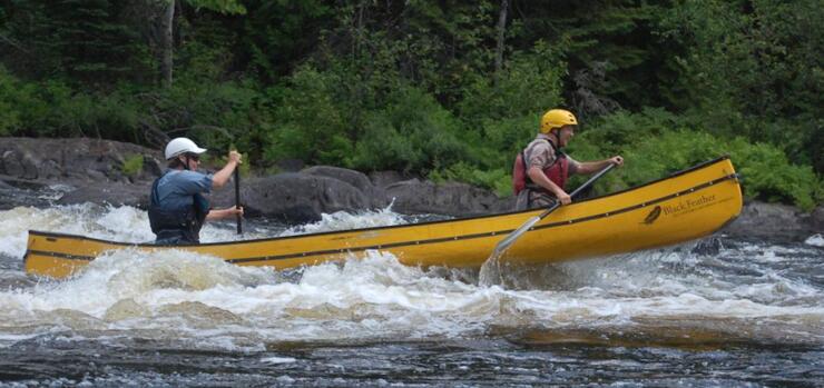 Two people in a yellow canoe in rapids. 