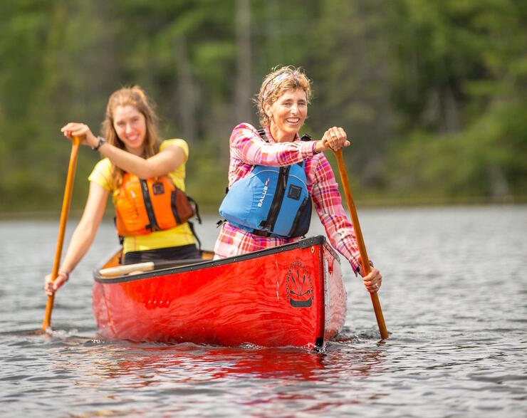 Two women paddling a red canoe 