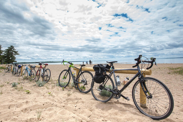 a group of bicycles parked at the edge of a sandy beach