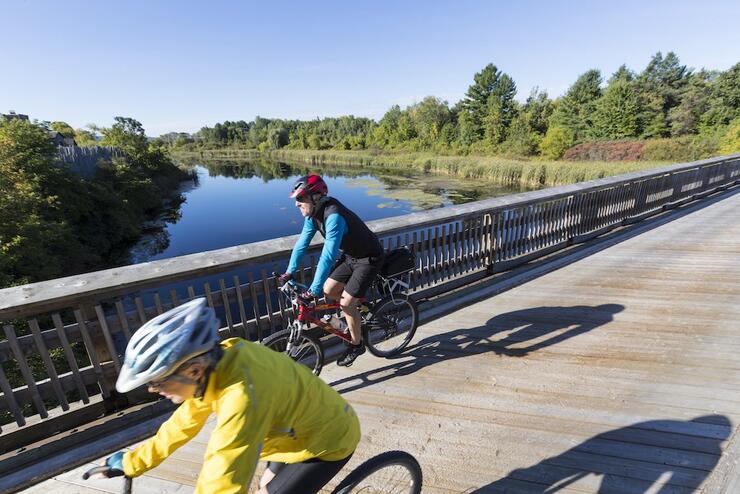 Two people biking across wooden bridge