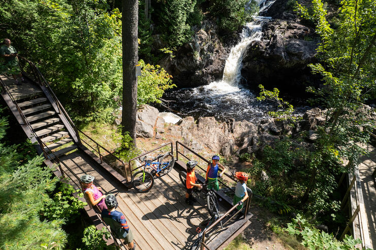 Group of cyclists stop at a boardwalk to view a waterfall